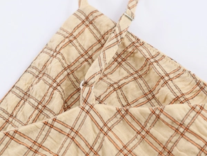 Détail de la robe d'été à carreaux jaunes avec bretelle réglable et boucle en métal