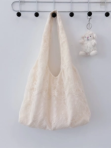 Elegant cream lace tote bag with floral embroidery and cute lamb pendant on a stand