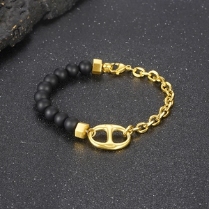 Macro detail of gold pig nose buckle with matte black beads and golden metal link chain