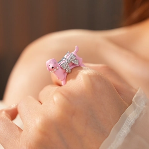Detail of pink puppy ring with pearl collar and rhinestone bow on a finger