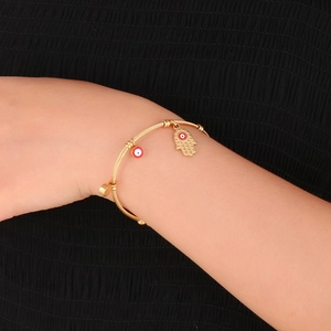 Detailed close-up of 18K gold stainless steel evil eye bangle on a model wrist