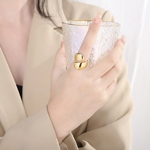 Detail of a polished gold minimalist open ring worn by a model in elegant professional attire