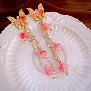 Détails des boucles d'oreilles papillon avec perles roses et fleurs de muguet suspendues