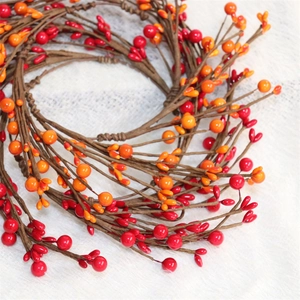 Artificial red berry wreath for Christmas and autumn decor on white plush background