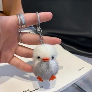 Close-up of handmade mink fur yellow duck keychain with silver ring and soft texture