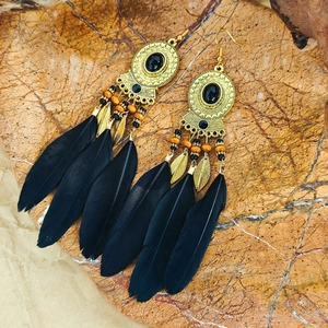 Detail of bohemian earrings with black feathers and intricate metal hollow discs