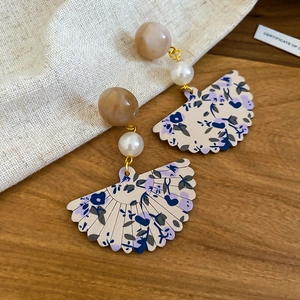 Detail of vintage fan-shaped earrings with resin pearls and blue floral pattern charms