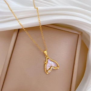 Detailed shot of golden mermaid tail pendant with colorful gems on white satin fabric