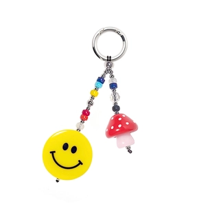 Cute beaded keychain with yellow smiley face and red mushroom charms on white background