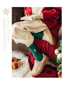 Détail de chaussettes de Noël vert forêt avec broderie renne et texture tricotée