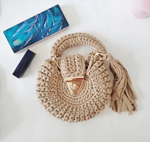 Detail of hand-woven round crochet bag featuring a gold lock and long side tassels