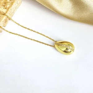 Détail du collier pendentif coquillage doré avec zircons brillants sur fond de soie
