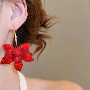 Close-up of red resin flower earrings with gold hooks worn on model for a sweet style