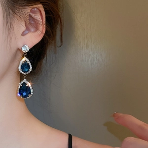 Macro shot of silver-tone drop earrings with double dark blue gemstones and crystal halo