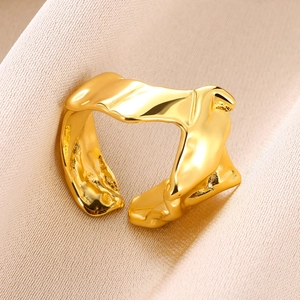 Detailed close-up of golden open ring with irregular lava texture on silk background