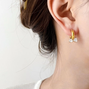 Close-up of golden heart zircon earrings worn by a model in a minimalist setting