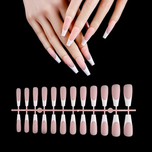 Macro view of long trapezoid French press-on nails with nude pink base and white tips