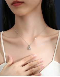 Detail of S925 silver bow necklace with a sparkling heart zircon on a woman collarbone