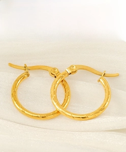 Detail view of gold vintage hoop earrings with spiral texture on white fabric