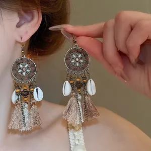 Bohemian vintage tassel drop earrings with shell accents and wooden beads on model