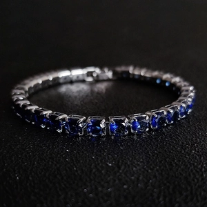 Macro shot of silver tennis bracelet featuring square-cut deep blue zircons in 4-claw setting