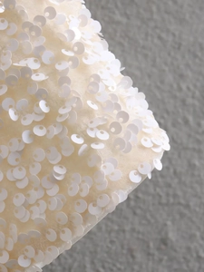 Macro shot of dense white sequins on cream fabric for a luxury short jacket