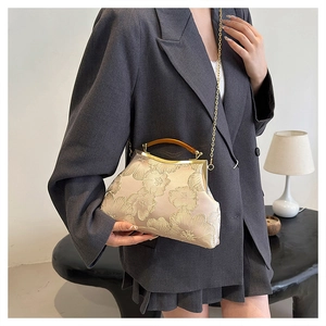 Detail of vintage beige satin bag with floral embroidery and amber handle on model