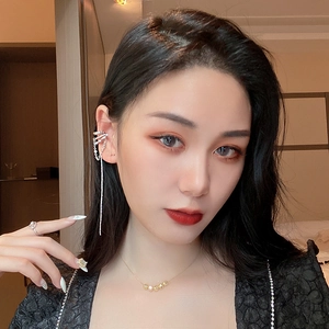 Close-up of model wearing long tassel earrings with rhinestones and faux pearls