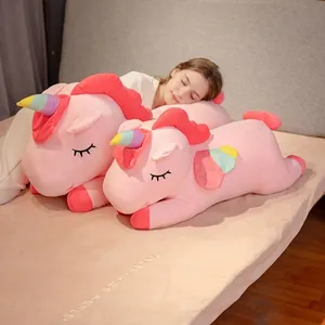 Pink plush rainbow unicorn pillow doll for kids lying on a bed in a cozy bedroom