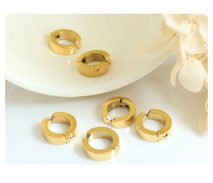 Close-up of 18k gold plated titanium steel clip-on earrings on a ceramic dish