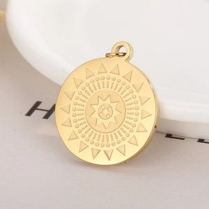 Macro shot of circular gold stainless steel pendant featuring sunburst and star engraving