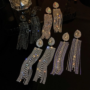 Detail of teardrop rhinestone tassel earrings in multiple colors on a dark reflective base