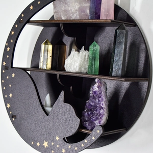 Detail of a black moon-shaped wooden shelf featuring a cat silhouette and crystals
