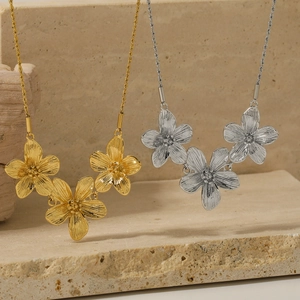 Französische Vintage Blumenketten in Gold und Silber auf einem strukturierten Stein