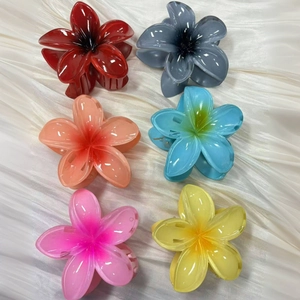 Colorful resin frangipani flower hair claws in six gradient shades on white fabric
