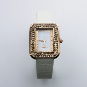 Detail of square gold watch case with crystal bezel and white crocodile leather strap