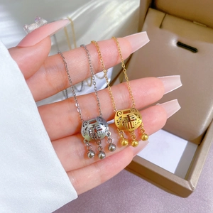 Detail of gold and silver longevity lock necklaces with bells held by a model
