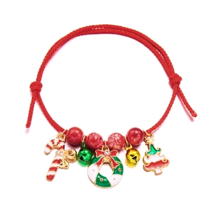 Detail of red braided Christmas bracelet with festive charms like tree and bells