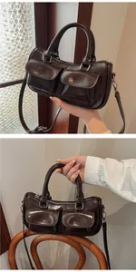 Detail view of deep brown patent leather saddle bag with pockets and adjustable strap