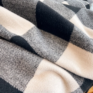 Close-up detail of soft black, grey, and beige checkered knit fabric texture