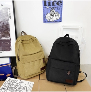 Detail view of khaki and black canvas backpacks with front pockets on display