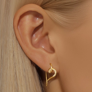 Close-up of golden heart-shaped zircon earrings worn on a model for an elegant look