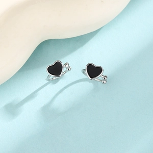 Close-up of black heart clip-on earrings with silver metal edges on blue background