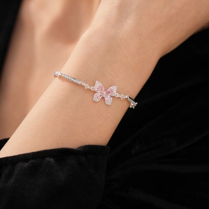 Détail d'un bracelet papillon avec ailes en zircon rose sur fond de velours noir