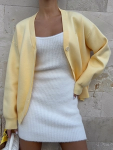 Detail of light yellow knit cardigan layered over a white plush textured midi dress