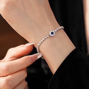 Detail of silver tennis bracelet with blue zircon flower and white diamond accents