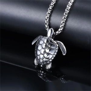 Silver turtle pendant necklace with detailed shell texture on a reflective black surface