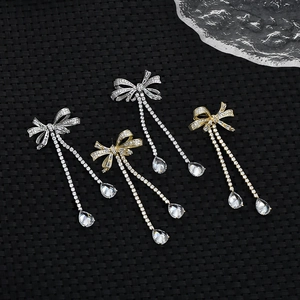 Macro shot of cubic zirconia bow earrings with sparkling tassels on black textured background
