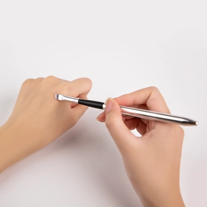 Angled eyebrow brush with silver metal handle and synthetic fibers for precise makeup application