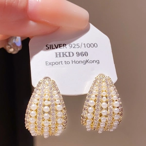 Detailed macro view of gold earrings with pavé crystals and white pearls on silver base